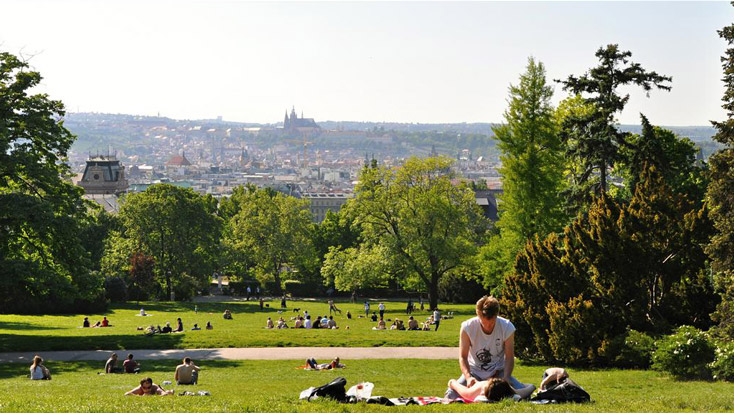 Young people enjoy the sunshine with a view of the Castle and Old Town at Riegrovy Sady